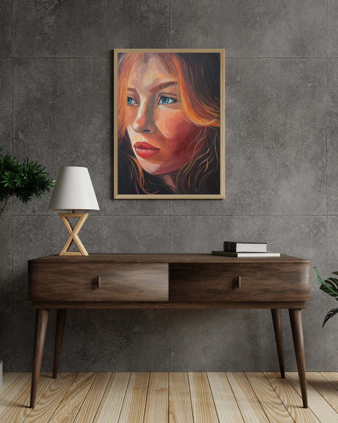 A framed portrait painting of a woman with warm orange and red hair, blue eyes, and red lips, hanging on a textured gray concrete wall above a mid-century modern wooden console table with a lamp and books.
