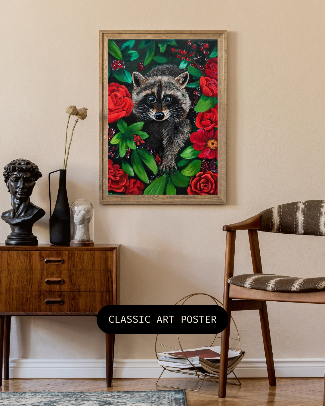 A framed art print depicting a raccoon surrounded by red roses and green leaves, displayed on a beige wall in a styled room with a wooden sideboard, chair, and decorative busts.